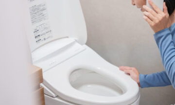 トイレのトラブルで水道業者に電話する女性